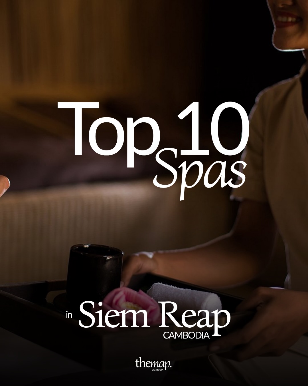 Spa therapist in Siem Reap carrying a tray with a lotus flower and rolled towel in a dimly lit treatment room