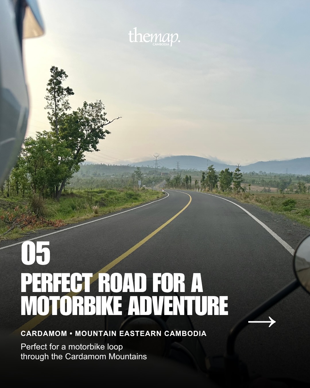 A motorbike view of an empty road curving through the Cardamom Mountains